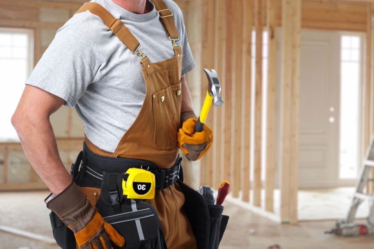 A man holding a hammer and wearing an apron.